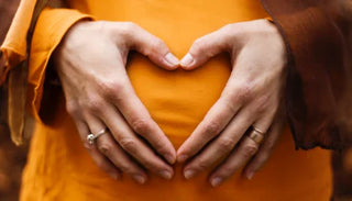 Gravid kvinna formar ett hjärta med händerna på magen – intimitet, kärlek och sex under graviditeten