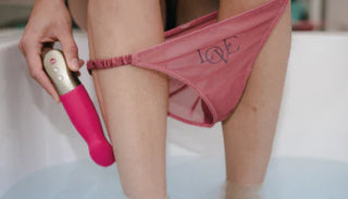 Kvinna i rosa trosor håller en vibrator i badet – faktorer som påverkar sexlust och njutning
