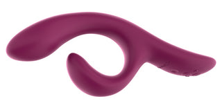 En We-Vibe Nova 2 Rabbitvibrator, en lila böjd silikonvibrator med dubbla ändar och en flexibel klitorisstimulator, vilar mot en vit bakgrund.