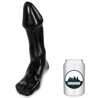 En "Anal Plugg Med Fot" svart fotformad skulptur gjord av mjukt gummi placeras bredvid en burk för storleksjämförelse.