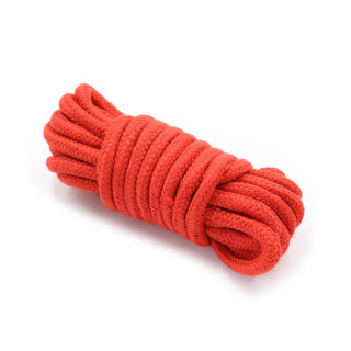 En snyggt inlindad spole av rött rep, perfekt för att förbättra ditt IntoYou 10-Delar Bondage Kit, står slående mot en vit bakgrund.