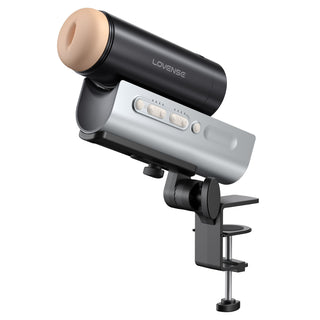 En svart och beige Lovense Solace Pro 2 kläms fast på en plan yta och visas från sidan, med appstyrning för sömlös kontroll.