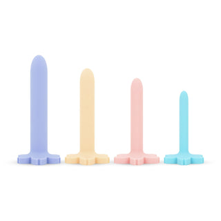 Teazers Vagina Dilator Set 4 Delar har fyra pastellfärgade silikon-dilatatorer - lila, gul, rosa och blå - som står upprätt på en vit bakgrund, utformade för mild slidmuskulaturträning på ett vänligt sätt.