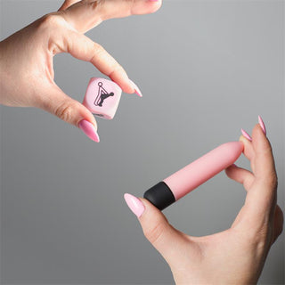 En hand håller Secret Play Bullet & Tärningskit - en rosa kula och sexställningstärning - perfekt för ditt sensuella känslokit eller för att upptäcka nya sexleksaker för par.