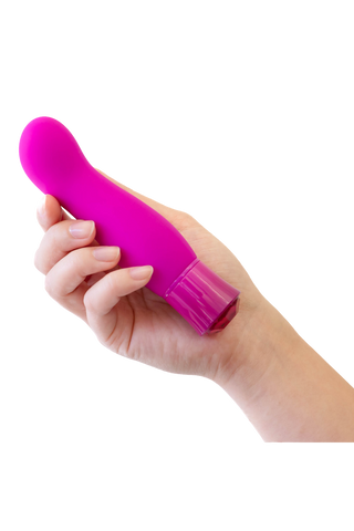 En hand håller i Exclusive Tourmaline Vibrator, en liten, rosa, böjd G-punktsvibrator med värmefunktion, mot en vit bakgrund.