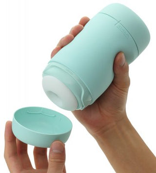 Händer som håller en grön cylindrisk Tenga Puffy Masturbator Mint Grön med ett avtagbart lock, med en innovativ mjuk silikon-design för ökad komfort.