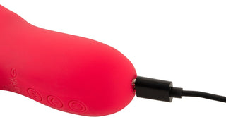 En närbild av Thumping Rabbitvibrator, som visar upp dess röda böjda design med tre knappar på slät silikon, ansluten till en svart laddningskabel.