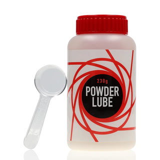 En vit behållare med Powder Lube med rött lock och virvlande design sitter bredvid en genomskinlig mätsked, vilket ger en justerbar konsistens för dina behov.