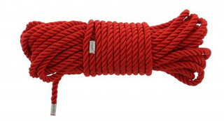 Blaze Deluxe Bondage Rep 5 M, ett hoprullat knippe av rött rep, sticker dramatiskt ut mot en vit bakgrund och återspeglar essensen av traditionell shibari-konst.