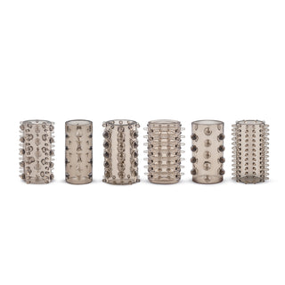 Sex genomskinliga, cylindriska penishylsor med texturerade mönster av spikar, stjärnor, ringar, cirklar och rutnät är riktade i rad på en vanlig vit bakgrund. Njut av extra stimulans för varierat nöje med Penis Sleeve Set.