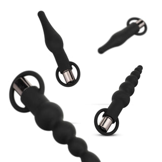En uppsättning av fyra snygga svarta silikonpluggar med metalliska baser och handtag, presenterade mot en orörd vit bakgrund. Produkt: Analpluggset med kulvibrator.