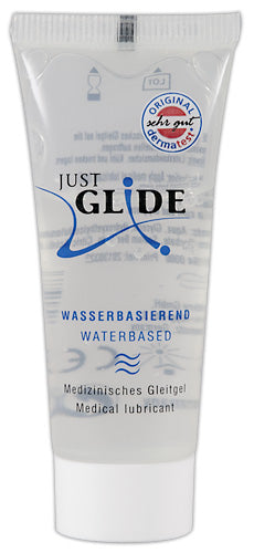 En genomskinlig tub med Just Glide Waterbased Glidmedel visar upp en blå och vit etikett med "wasserbasierend" och "waterbased". En cirkulär blå tätning med "Original dermatest sehr gut" garanterar kvalitet för detta vattenbaserat glidmedel.