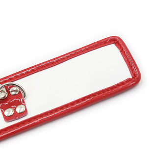 Ohmama 3-delade Nurse Bondage Set har en vit paddel med en blank röd kant, metallnitar på handtaget och en D-ring. Denna slående paddel förstärker fetischlek och inbjuder till fantasifulla rollspel mot dess kontrastiva enkla bakgrund.