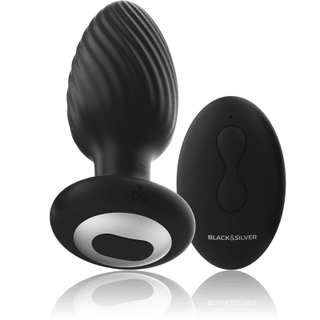 Black&Silver Wells Fjärrstyrd Buttplug, i kroppsvänlig silikon, har en svängd design med en svart strukturerad finish. Den innehåller en fjärrstyrd fjärrkontroll som visar etiketten "BLACK & SILVER". Basen har "DC" och en knapp, vilket ger en elegant modernitet.