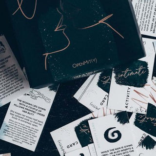 Abstrakta designkort med text är utspridda på en yta. Det upplysta kortet har konturerade ansikten och ordet OPENMITY, vilket framkallar det engagerande spelet i Love Battleship Premium Edition. Andra kort visar olika mönster i olika orienteringar.