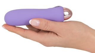 En hand håller Cuties - Vibrator 12 cm, en elegant, lila, kulformad minivibrator med metallspets gjord av slät silikon.