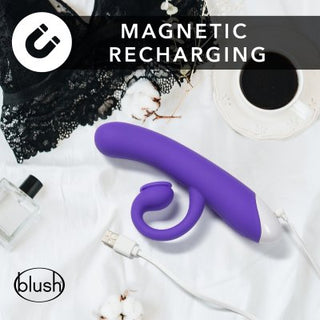 En lila HOP - Oh Bunny - Sugande Rabbitvibrator 19 cm med magnetisk laddning vilar på ett vitt lakan, tillsammans med ett spetsplagg och kaffekopp, allt tillverkat av slätt silikonmaterial.