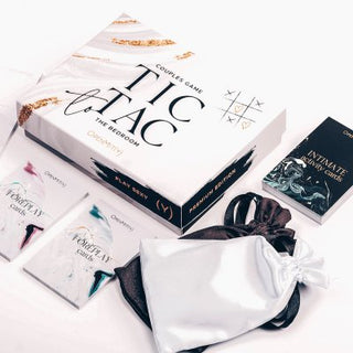 Tic Tac To The Bedroom Premium: ett lekfullt parspelsset med kort och påsar, perfekt för att förstärka din kontakt med förspelsaktiviteter och kryddiga frågor för att tända passion. Elegant arrangerad på en vit yta.