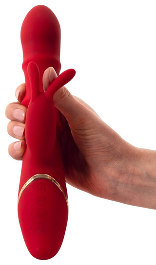 En hand håller en snygg, röd You2Toys Rabbitvibrator med flera inställningsknappar för olika vibrationslägen, vilket säkerställer en personlig upplevelse.
