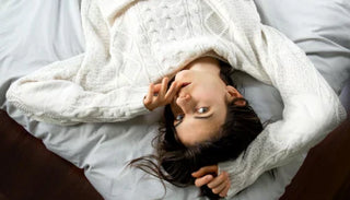 Kvinna liggande på sängen med sensuell blick – symbol för njutning och effekten av orgasmgel.