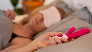 Kvinna som ligger i sängen och håller i en rosa rabbit vibrator för klitorisstimulans och G-punktsstimulans