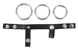 Svart läderpenisband med tre utbytbara metallringar, justerbar design, fotograferat mot vit bakgrund.