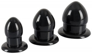 Anal Stretching Plug Kit innehåller tre svarta silikonpluggar i olika storlekar, arrangerade från minsta till största, med släta, glänsande ytor och runda baser, idealiska för säker analstimulering.