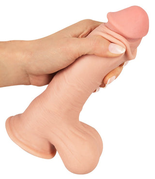 En hand håller en Nature Skin Realistisk Dildo 20 cm, som visar upp detaljerad struktur och en robust sugkopp bas.