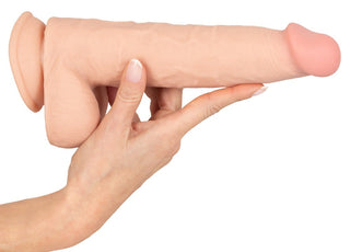 En hand som håller i Nature Skin Realistisk Dildo 25 cm, ett beige cylindriskt föremål med både släta och strukturerade ytor som påminner om naturens hud.