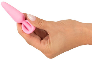 En hand håller Cuties Mini Buttplug Rose, en rosa silikonplugg med ringhandtag.