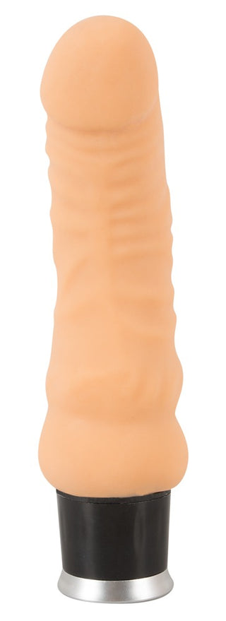 En hudfärgad, realistisk vibrator med en svart-silverfärgad bas, tillverkad av hudliknande material, avbildad mot en vit bakgrund.