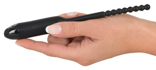 En hand håller Dilator Vibe Vibrerande Stimulator - en svart, pärlbeströdd, flexibel silikon-dilatator med ett rundat handtag; en snygg och diskret sexleksak i silikon.