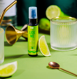 Intt Lick Me Caipirinha Ätbar Gel 50ml visas med limeklyftor, ett glas, en sked och cocktailverktyg på en grön yta - perfekt för cocktails eller för att utforska ätbar gel för oralsex med en värmande effekt.