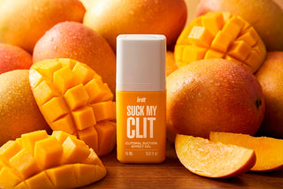 En genomskinlig plastflaska med Intt Suck My Clit Tropical Mango-gel, med en gul etikett och en pumpdispenser.