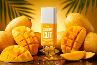 Intt Suck My Clit Tropical Mango-flaska, med orange och gul etikett, i plastförpackning, avbildad stående på en enfärgad bakgrund.