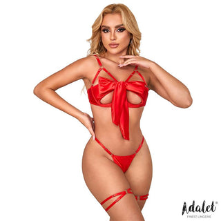 Modell i Riley Röd Rosett-Lingerieset – röd satin stringtrosa och strumpeband med rosettdetalj – poserar självsäkert med en hand på höften mot en vit bakgrund.