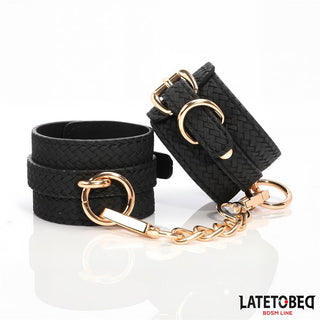 Handbojor Med Guldfärgad Kedja - svarta handbojor i flätat läder med guldfärgad kedja och detaljer. En elegant BDSM-accessoar från LATETOBED BDSM LINE (etikett nederst till höger).