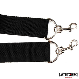 Närbild av två Latetobed Shoulder Swingstrap svarta nylonremmar med metallklämmor och -ringar, mot en vit bakgrund.