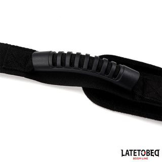 Närbild av Latetobed Shoulder Swingstrap, med en svart nylonrem och ett räfflat gummihandtag; LATETOBED BDSM LINE-logotypen visas i hörnet.