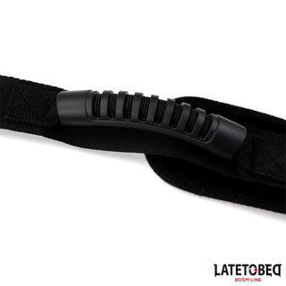 Närbild av Latetobed Shoulder Swingstrap, med en svart nylonrem och ett räfflat gummihandtag; LATETOBED BDSM LINE-logotypen visas i hörnet.