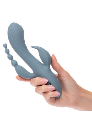 En hand håller i Triple Ecstasy Vibrator, en grå, multifunktionell personlig massageapparat med olika texturerade tillbehör, gjord av kroppssäker silikon och med en vattentät-design.