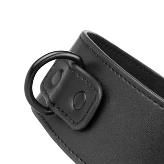 Närbild på Halsband & Handledsbojor, ett svart justerbart läderhalsband med metall-D-ring och två svarta nitar – perfekt för BDSM-lekar eller som handledsband.
