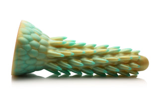 Stegosaurus Dildo Silikon är en texturerad, pastellgrön och gul silikondildo med ett skalliknande mönster, som påminner om en dinosaurie, som visas liggande på sidan.