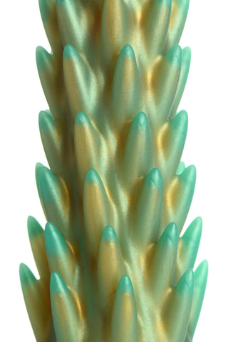 Närbild av Stegosaurus Dildo Silikon, ett grönt och guldfärgat spetsigt föremål som liknar en stiliserad växt eller kaktus, mot en vit bakgrund.