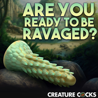 En Stegosaurus Dildo Silikon, inspirerad av drakar, vilar på en sten med texten "ARE YOU READY TO BE RAVAGED?" ovanför.