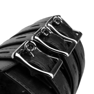 Närbild av tre silverfärgade spännen på en svart läderrem med justerbara remmar, del av Armfängsel Sele Svart, designad för bondage, mot en vit bakgrund.