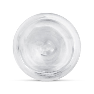 En rund, silverfärgad metallplatta sedd uppifrån mot en vit bakgrund, bredvid Transparent Jellydildo 20 cm.
