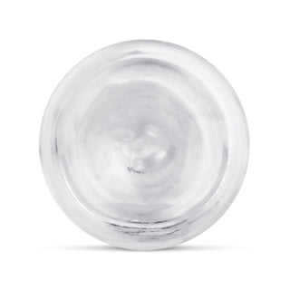 En rund, silverfärgad metallplatta sedd uppifrån mot en vit bakgrund, bredvid Transparent Jellydildo 20 cm.