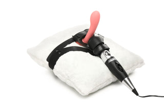 XR Brands Thunder Strap, en rosa strap-on dildo med en svart sele fäst vid en vit kudde, visas tillsammans med en handhållen stavvibrator.