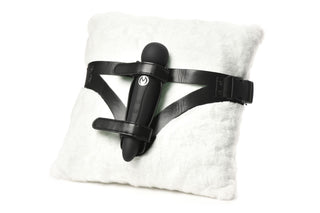XR Brands Thunder Strap, en svart strap-on-sele med en stavvibrator monterad, visas elegant på en fluffig vit kudde.